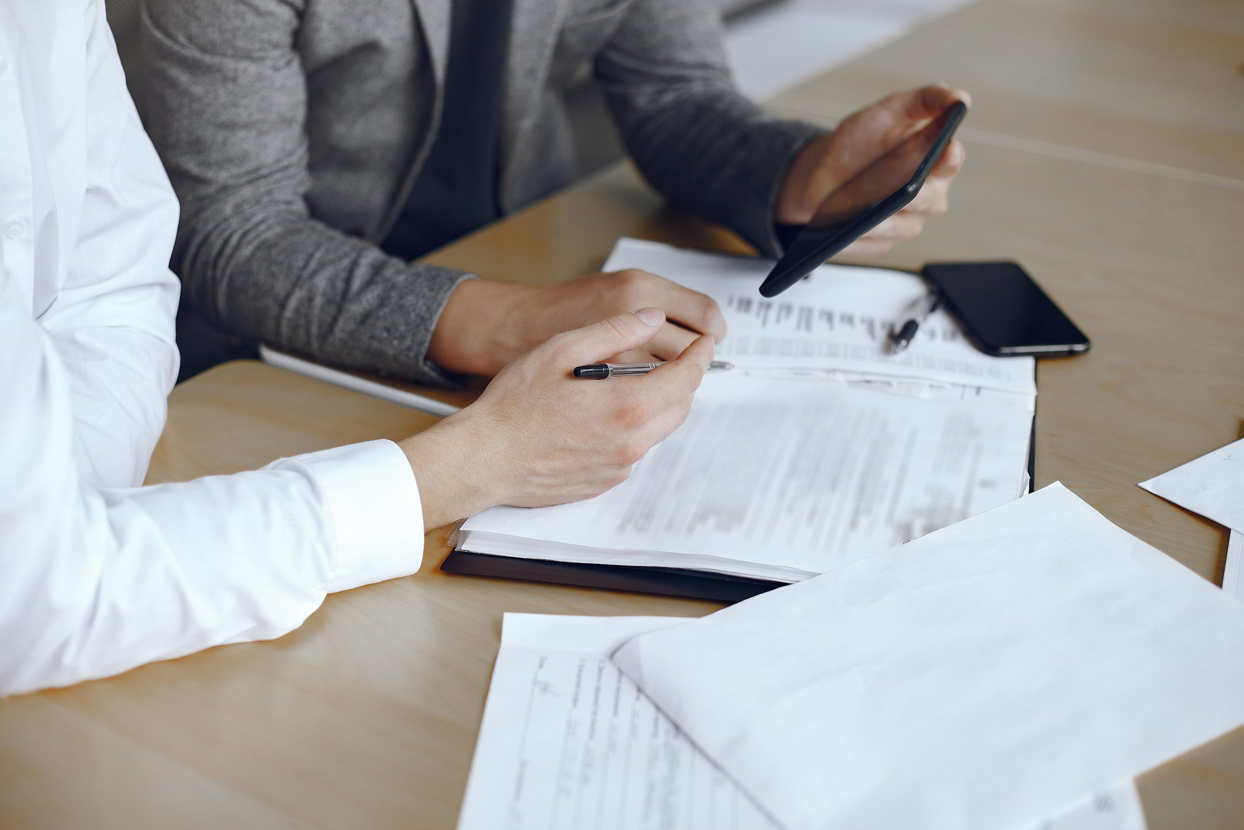 Two business partners signing a document Business men sitting at the lawyers's desk. People signing important documents.